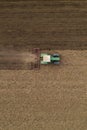 Aerial view of agricultural tractor tilling and harrowing ploughed field, directly above drone pov