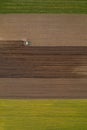 Aerial view of agricultural tractor tilling and harrowing ploughed field, directly above drone pov