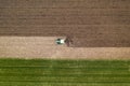 Aerial view of agricultural tractor tilling and harrowing ploughed field, directly above drone pov