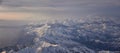 Aerial view from airplane of the Wasatch Front Rocky Mountain Range with snow capped peaks in winter including urban cities of Pro