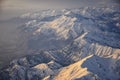 Aerial view from airplane of the Wasatch Front Rocky Mountain Range with snow capped peaks in winter including urban cities of Pro