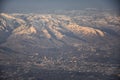 Aerial view from airplane of the Wasatch Front Rocky Mountain Range with snow capped peaks in winter including urban cities of Pro