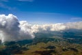 Aerial view from airplane window at high altitude of distant city covered with puffy cumulus clouds forming before rainstorm Royalty Free Stock Photo