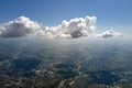 Aerial view from airplane window at high altitude of distant city covered with puffy cumulus clouds forming before rainstorm Royalty Free Stock Photo