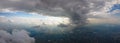 Aerial view from airplane window at high altitude of distant city covered with puffy cumulus clouds forming before Royalty Free Stock Photo