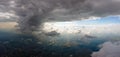 Aerial view from airplane window at high altitude of distant city covered with puffy cumulus clouds forming before Royalty Free Stock Photo