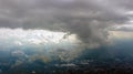 Aerial view from airplane window at high altitude of distant city covered with puffy cumulus clouds forming before Royalty Free Stock Photo