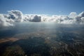 Aerial view from airplane window at high altitude of distant city covered with puffy cumulus clouds forming before Royalty Free Stock Photo