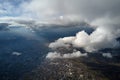 Aerial view from airplane window at high altitude of distant city covered with puffy cumulus clouds forming before Royalty Free Stock Photo