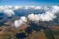 Aerial view from airplane window at high altitude of distant city covered with white puffy cumulus clouds Royalty Free Stock Photo