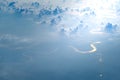 Aerial view from airplane window of white puffy clouds on bright sunny day ang glowing river Royalty Free Stock Photo