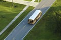 Aerial view of american yellow school bus driving on suburban street for picking up children for their lessongs in early