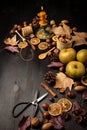 Aerial view of apples, lit candle, nuts, oranges, scissors and autumn leaves, on a dark wooden background, vertically,