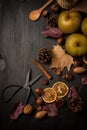 Aerial view of apples, nuts, oranges, cinnamon, scissors and autumn leaves, on a dark wooden background, vertical,