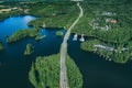 Aerial view of asphalt road with cars over blue lake and green woods in Finland Royalty Free Stock Photo