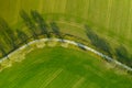 Aerial view on a asphalt road separated two cultivated fields. Top view on a motorway between farmers lands Royalty Free Stock Photo