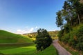 Aerial view of asphalt road winding through lush green hill in rural area under blue sky Royalty Free Stock Photo