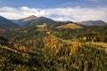 Aerial view of autumn mountain landscape with evergreen pine trees and yellow fall forest with magestic mountains in distance Royalty Free Stock Photo