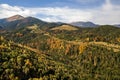 Aerial view of autumn mountain landscape with evergreen pine trees and yellow fall forest with magestic mountains in distance Royalty Free Stock Photo