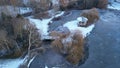 Aerial view of a bandstand on the frozen lake's surface, surrounded by bare trees on a winter day