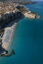 Aerial view of a beach with umbrellas and bathers. Houses on the rock and beach. Promontory. Tropea, Calabria, Italy.