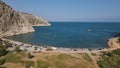 Aerial view of a beautiful cove with a sandy beach, clear water and cliffs on a sunny day Royalty Free Stock Photo