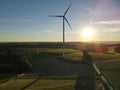 Aerial view of a landscape with agriculture fields, a road and a wind turbine on a sunny evening in summer