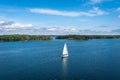Aerial view of beautiful modern white sailing yacht sails on the sea surface on sunny summer day. Shot from cruise ship. Forest Royalty Free Stock Photo
