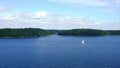 Aerial view. Beautiful modern white sailing yacht sails on the sea surface on sunny summer day. Shot from cruise ship. Forestly