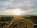 Aerial view beautiful panoramic landscape golden sunset above the forest. The road goes beyond the horizon in the rays of the sun Royalty Free Stock Photo