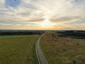 Aerial view beautiful panoramic landscape golden sunset above the forest. The road goes beyond the horizon in the rays of the sun Royalty Free Stock Photo