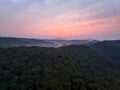 Aerial view of beautiful pink clouds over misty forested landscape