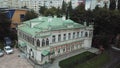 Aerial view of a beautiful restored building with many windows, white facade, and green roof. Stock footage. Vintage
