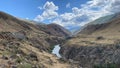 Aerial view of the beautiful rocky mountains and the stormy river. Blue sky and white clouds