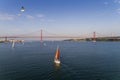 Aerial view of a beautiful sail boat on the Tagus River with the 25 of April Bridge on the background, in the city of Lisbon, Port Royalty Free Stock Photo