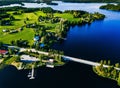 Aerial view beautiful summer landscape with blue lake, green fields and wooden houses. Countryside road with bridge in Finland Royalty Free Stock Photo