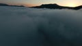 Aerial view of a beautiful sunrise above mountains and thick fog. Shot. Amazing flight above white clouds towards Royalty Free Stock Photo