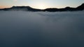 Aerial view of a beautiful sunrise above mountains and thick fog. Shot. Amazing flight above white clouds towards Royalty Free Stock Photo