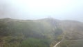 Aerial view of beautiful young couple in white clothes standing on the top of cliff near the precipice in a heavy fog Royalty Free Stock Photo