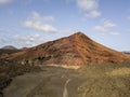 Aerial view of the Bermeja mountain of an intense red color, surrounded by lava fields, Lanzarote, Canary Islands, Spain