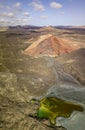 Aerial view of the Bermeja mountain of an intense red color, surrounded by lava fields, Lanzarote, Canary Islands, Spain