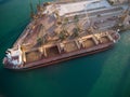 Aerial view of big cargo ship bulk carrier is loaded with grain of wheat in port at sunset