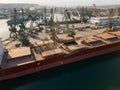 Aerial view of big cargo ship bulk carrier is loaded with grain of wheat in port at sunset