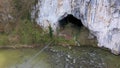 Aerial view of a big cave entrance and mountain river by drone, Unguru Mare cave, Suncuius, Romania