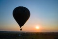 Aerial view of big hot air baloon flying over rural countryside at sunset Royalty Free Stock Photo