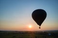 Aerial view of big hot air baloon flying over rural countryside at sunset Royalty Free Stock Photo