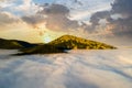 Aerial view of a big mountain over white dense clouds at bright sunrise