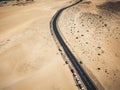 Aerial view of black asphalt road in the middle of the beach - desert around and concept of travel and vacation.   tropical scenic Royalty Free Stock Photo