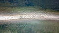 Aerial view of black birds on the white beach peninsula surrounded by water from both sides