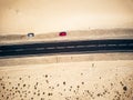 Aerial view of black straight asphalt road with sand and desert on both sides around - two car parked on the side - concept of Royalty Free Stock Photo